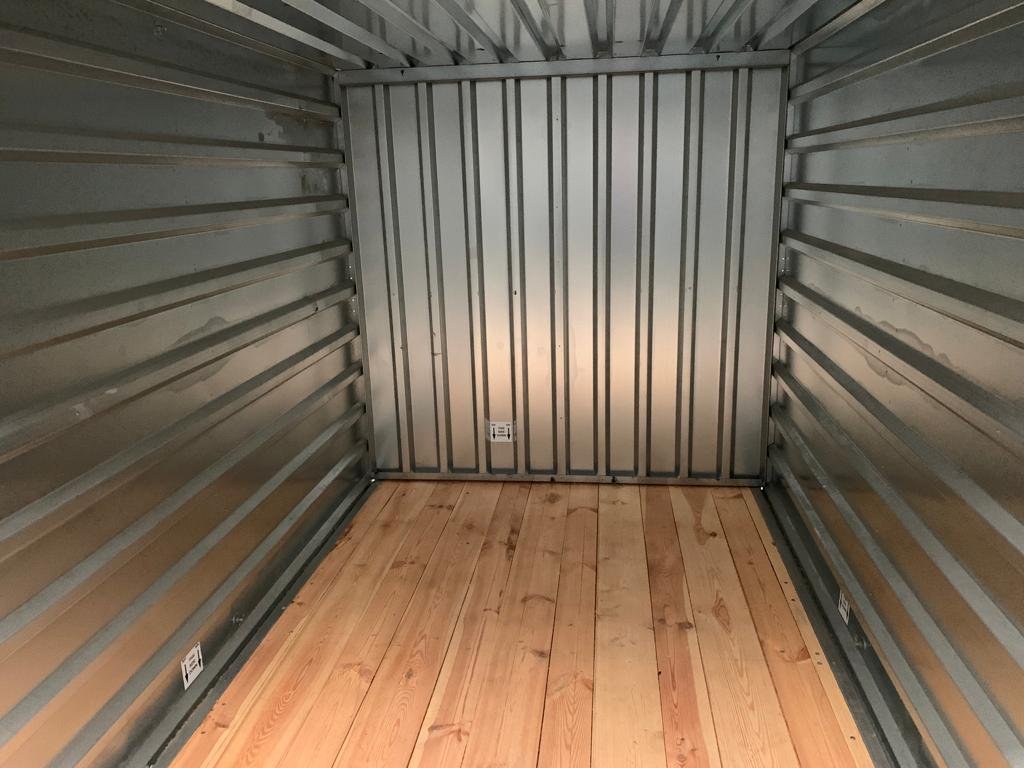 Inside an empty indoor storage unit, with galvanised steel walls and a pale timber floor